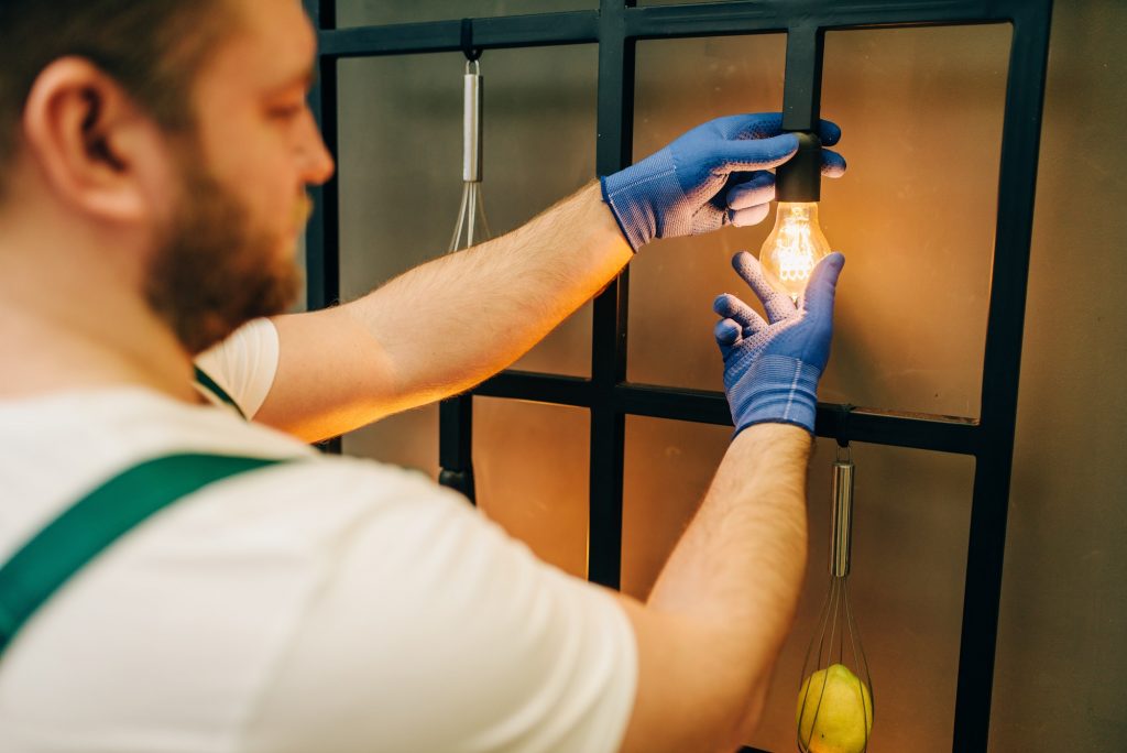 Electrician changes the light bulb, handyman